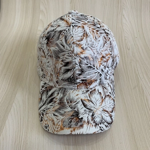 Détail de casquette blanche avec motifs de feuilles brunes et coutures à six panneaux