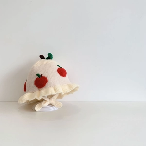 Detailed knit of baby bonnet featuring red apple pattern and ruffled edge with straps