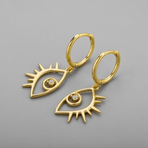 Detailed view of luxury gold eye-shaped earrings with sparkling white crystals