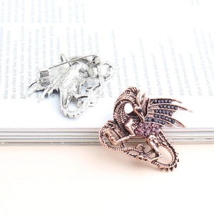 Fashionable dragon brooch set with crystal accents displayed on an open vintage book page