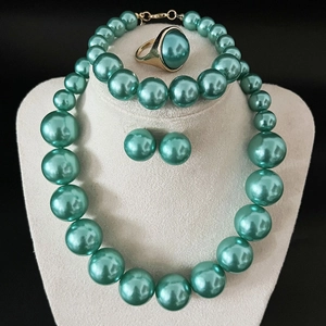 Detailed view of turquoise pearl necklace, earrings, and ring set on a beige jewelry bust