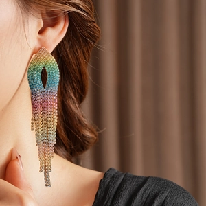 Close-up of elegant gradient rainbow rhinestone tassel earrings worn on ear model