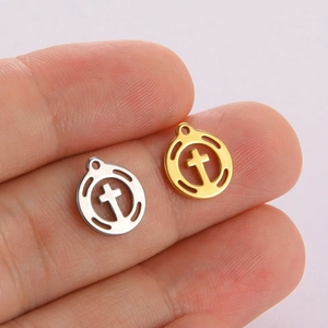 Detail of small 18K gold and silver cross pendants shown on a finger for scale
