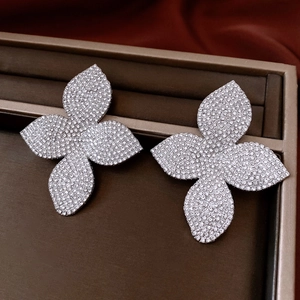 Gros plan de boucles d'oreilles fleurs argentées avec strass sur un plateau à bijoux brun