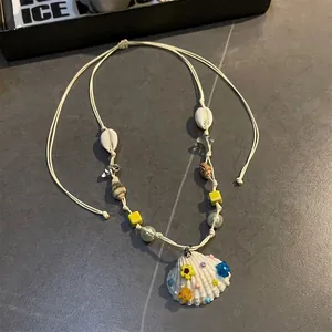Detailed macro view of sea shell pendant with colorful resin flowers on woven cord