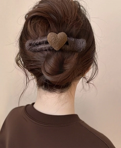 Detail of dark brown wool heart hair clip securing a hair bun on a female model