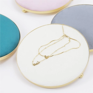 Detail of a double-layered gold necklace with love pendant on white velvet jewelry tray