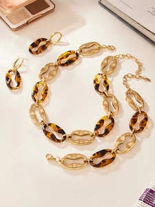 Close-up of vintage geometric gold metal and tortoise resin necklace and earring set