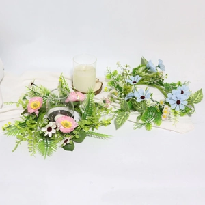 Detailed top view of pink and blue artificial floral garland with candles on white cloth