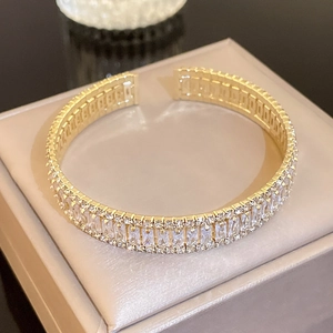 Detailed macro view of gold-tone open bangle with triple-row rectangular cubic zirconia stones