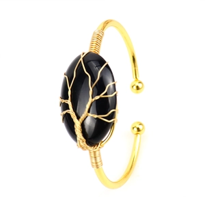 Close-up of handmade gold wire-wrapped oval black crystal cuff featuring Tree of Life detail
