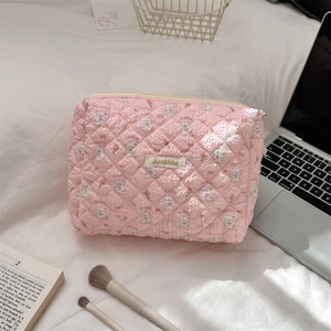 Close-up of quilted pink makeup bag with floral bunny print and metal brand label