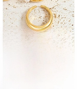 Detail of minimalist gold-plated ring featuring a white pearl inlay on a stone background