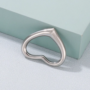 Minimalist silver hollow heart pendant on light green geometric stand with blue background