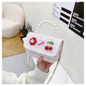 Detail of pink tweed mini crossbody bag with pearl handle and cherry decoration