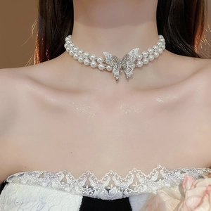 Detail of double-layer pearl necklace with a sparkling butterfly pendant on neck