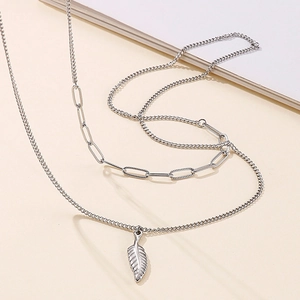 Silver double-layer wing necklace with paperclip chain and feather pendant on beige background