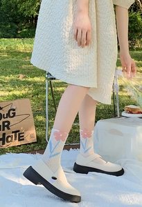 Close-up of white mesh floral jacquard socks paired with cream platform Mary Jane shoes