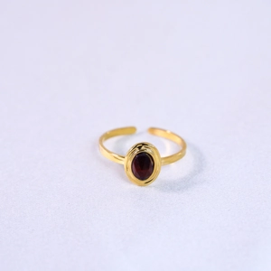 Macro detail of gold-plated open ring featuring an oval red natural stone inlay