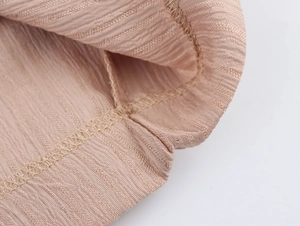 Gros plan détaillé du tissu texturé rose clair avec côtes verticales et couture soignée