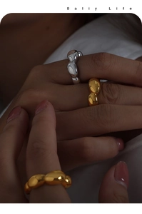 Close-up of organic melting geometric rings in gold and silver finish stacked on hand