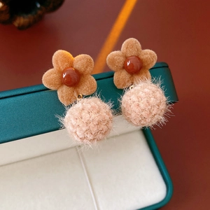 Macro shot of flocked flower earrings with soft pom-poms on a vintage velvet jewelry box