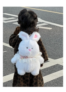 Outdoor shot of a child wearing a white plush bunny backpack with pink ears and lace detail