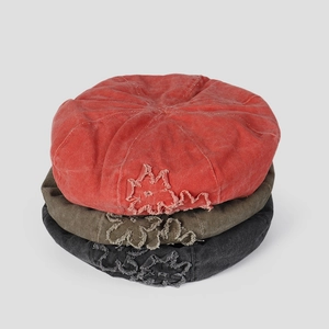 Detailed stack of vintage washed cotton berets in red, green, and black with floral patches