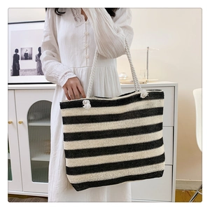 Detail of striped woven tote bag featuring thick rope handles and natural straw texture