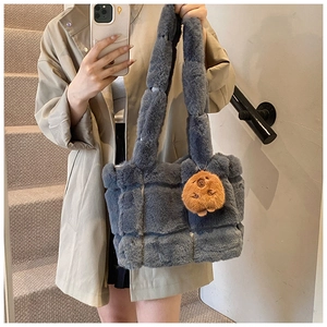 Detail of greyish-blue plush tote bag featuring a cute brown teddy bear pendant