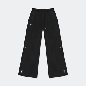 Detail of black cotton wide-leg sweatpants featuring white cross star embroidery and drawstring