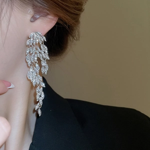 Close-up of elegant silver tassel leaf earrings with sparkling rhinestones on model