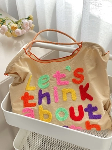 Detail of colorful towel embroidery lettering on beige canvas tote bag surface