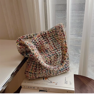 Multicolor woven shoulder bag with bohemian knit pattern on books and white curtains