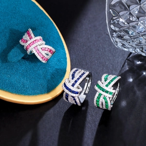 Three elegant knot rings with colorful crystals in red blue and green on a velvet tray
