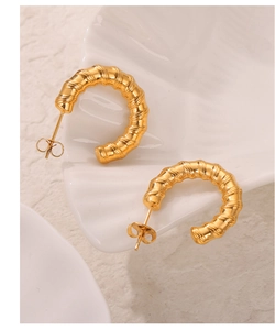 Detailed view of gold-plated titanium earrings with elegant twisted bamboo texture on a tray