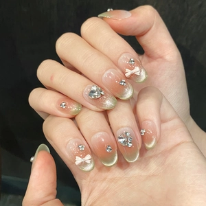 Cat eye press-on nails with pink-green gradient, silver rhinestones, and 3D white bow detail