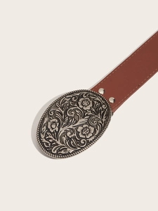 Detail of vintage brown leather belt featuring a large floral embossed silver buckle