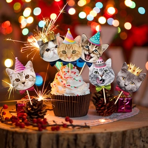 Close-up of cat face cake toppers with party hats on cupcakes with festive bokeh light