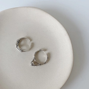Set of two silver S925 plated rings with chain texture and skull charm on a ceramic tray
