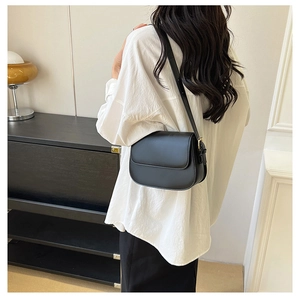 Detailed back view of a minimalist black leather saddle bag worn by a model