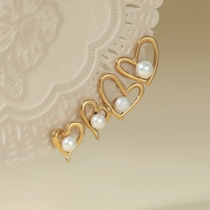 Elegant gold stainless steel hollow heart earrings with white pearls on lace background