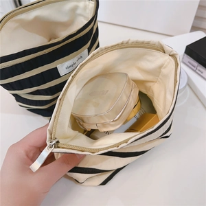 Macro view of a striped cotton makeup bag with brand label and sturdy metal zipper detail