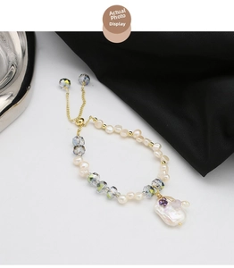 Detail of baroque pearl bracelet with iridescent crystals and golden floral accents