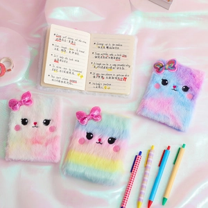 Flat lay of colorful plush cat notebooks with sequins bows on white silk background