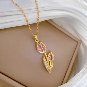 Detailed close-up of golden tulip necklace with pink gemstones on white silk background