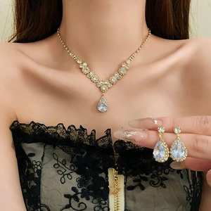 Detail showing elegant gold drop zircon necklace and matching earrings set on a model