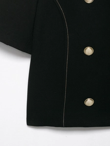 Close-up of black double-breasted blazer with gold buttons and contrast stitching details