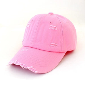 Detail of distressed pink cotton baseball cap with worn holes and vintage texture