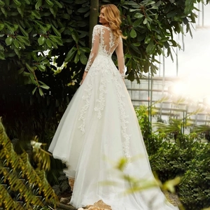 Elegante abito da sposa bianco a maniche lunghe con strascico lungo e ricami in pizzo